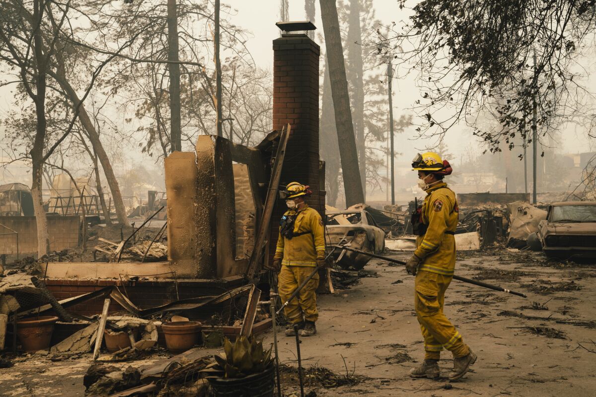 Firefighters stand in the remains of a house burned in the Camp Fire in Paradise, Calif., in 2018.
