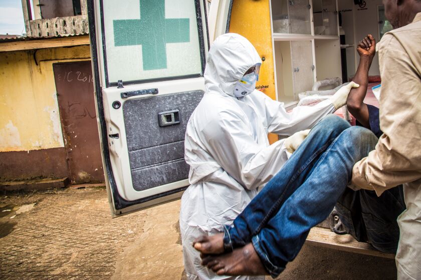 Health workers load a suspected Ebola patient into an ambulance in Freetown, Sierra Leone, in September 2014. The WHO recently released a one-year assessment of international efforts to combat the epidemic.