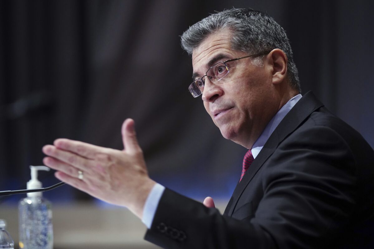 Xavier Becerra speaks at a microphone while seated.