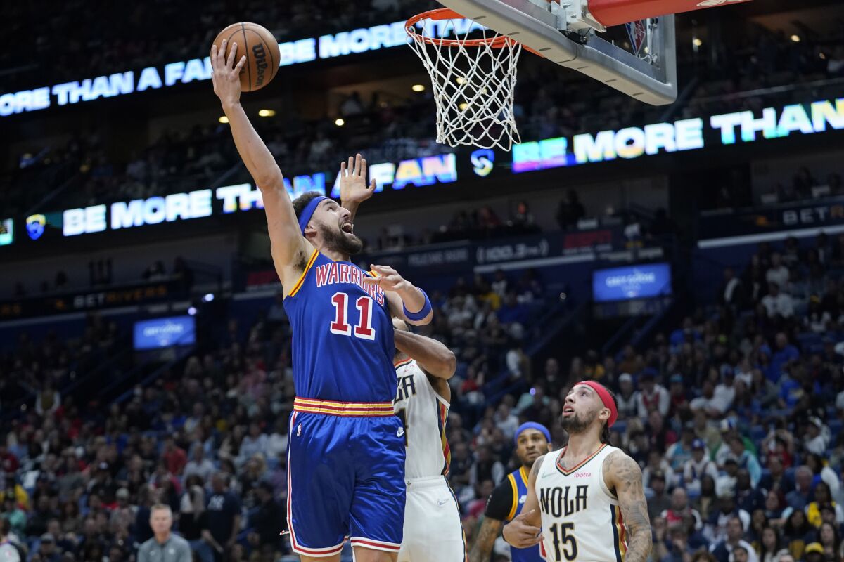 Golden State Warriors guard Klay Thompson (11) goes to the basket over New Orleans Pelicans guard Jose Alvarado (15) in the first half of an NBA basketball game in New Orleans, Sunday, April 10, 2022. (AP Photo/Gerald Herbert)