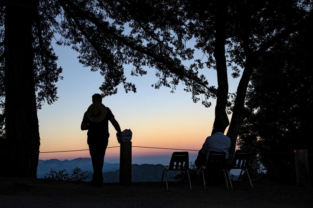 Silhouettes of two people taking in a sunset mountain view