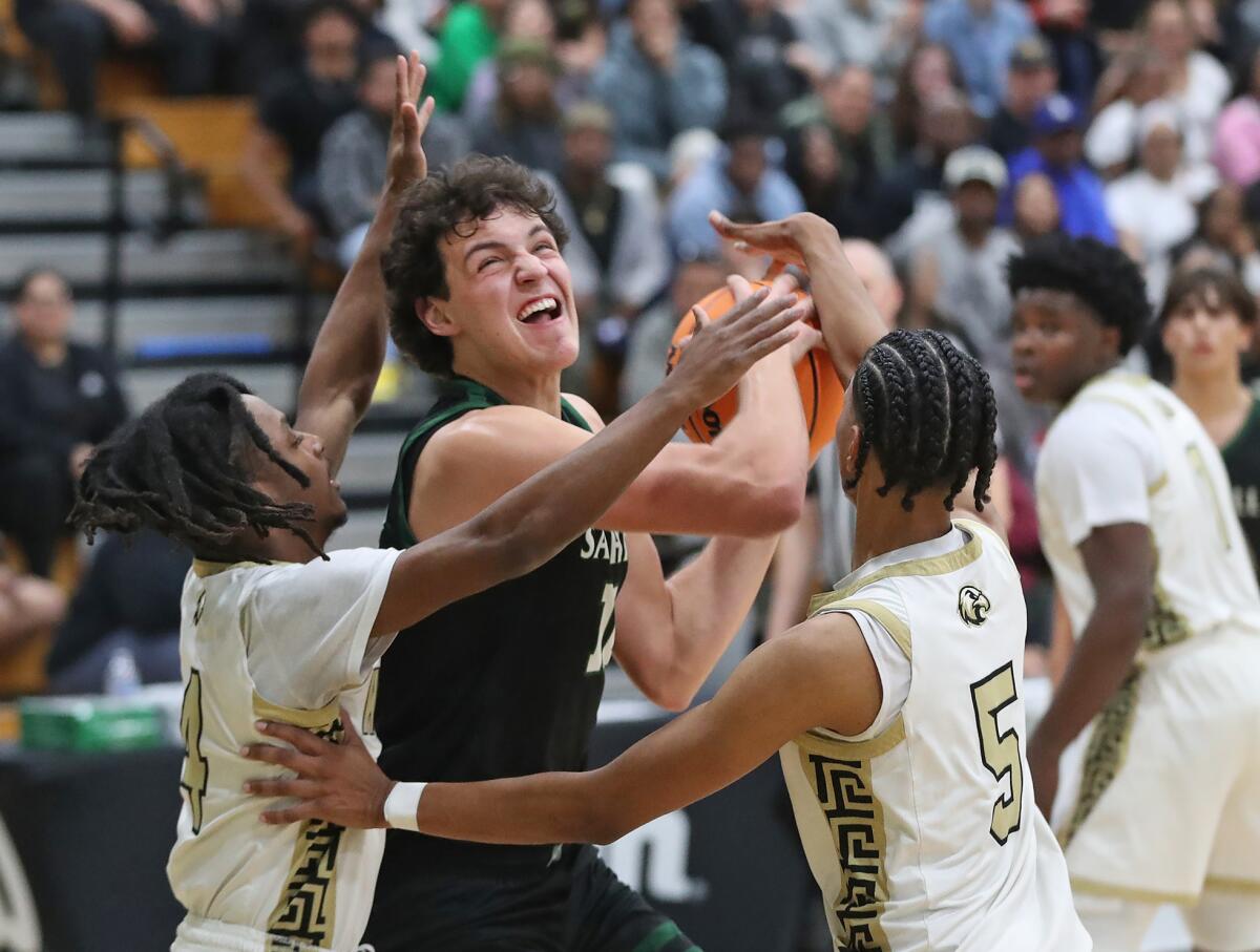 Sage Hill's Jackson Cryst (12) drives to the basket against Knight's Carson Claypool (4) and Da'Vian Brooks (5).