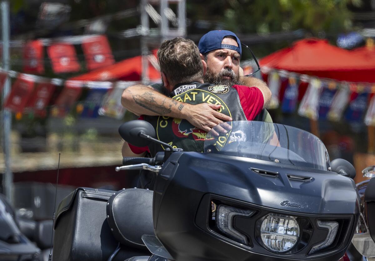 Members of a motorcycle club hug after their return to the scene of the mass shooting at Cook's Corner in Trabuco Canyon.