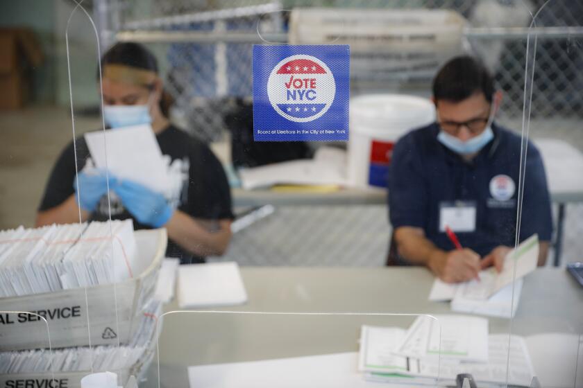 Workers wear personal protective equipment as they check ballots at a Board of Elections facility, Wednesday, July 22, 2020, in New York. (AP Photo/John Minchillo)