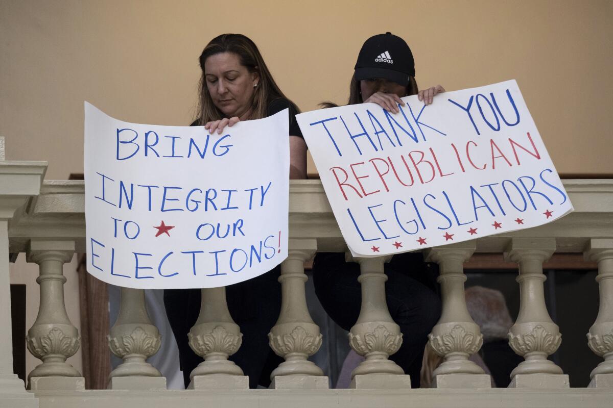 Protesters in favor of changes in Georgia's voting laws hold signs inside the State Capitol in Atlanta, Ga., as the Legislature meets Monday, March 8, 2021, in Atlanta. (AP Photo/Ben Gray)