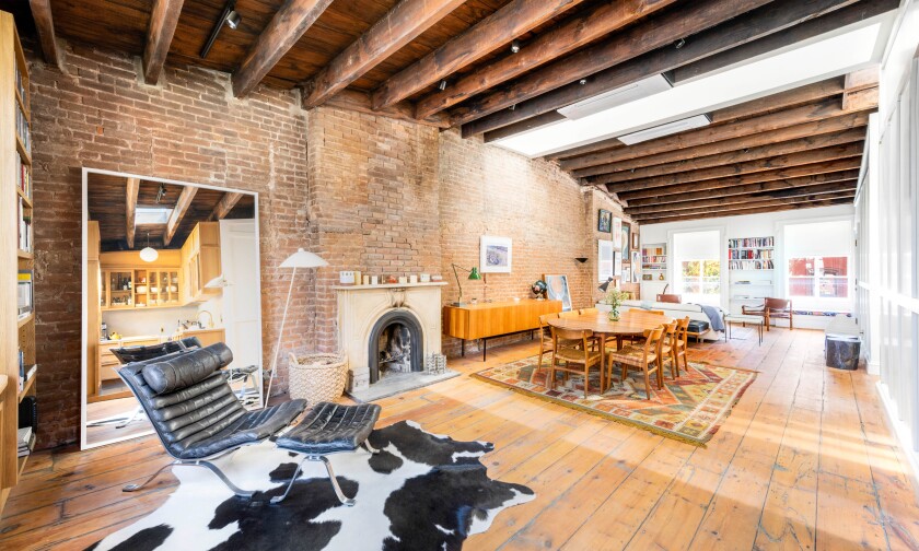 The prewar penthouse mixes old and new with exposed brick and rustic beams broken up by five skylights.
