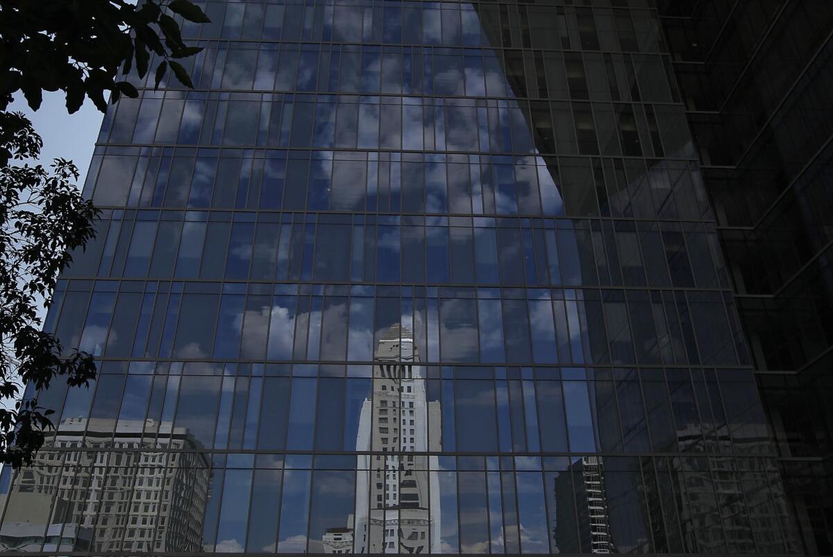 Los Angeles City Hall is reflected in the glass of the LAPD headquarters building. A city ordinance says motel guest records "shall be made available to any officer of the Los Angeles Police Department for inspection."