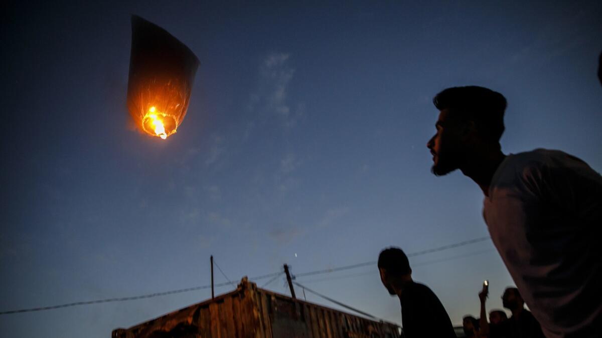 Palestinians watch a fire-bearing balloon. A growing proportion of the airborne flotilla has been made up of inflated condoms or party balloons bearing celebratory texts.