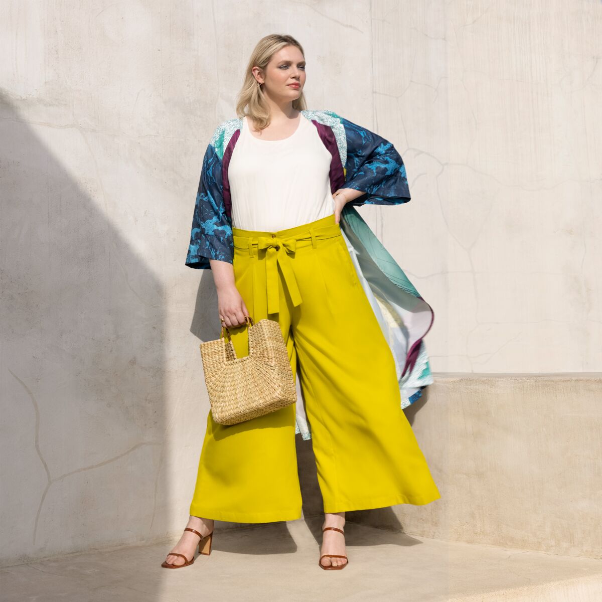 A woman modeling wide-leg yellow pants and a beach-inspired wrap