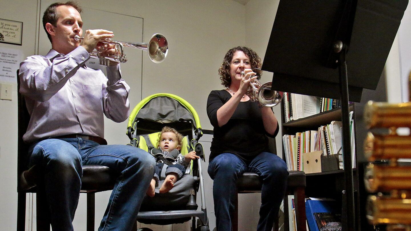 Thomas Hooten, L.A. Philharmonic principal trumpet, practices with his wife, Jennifer Marotta, while their son, Tommy, sits in at their La Crescenta home on Sept. 3, 2014.