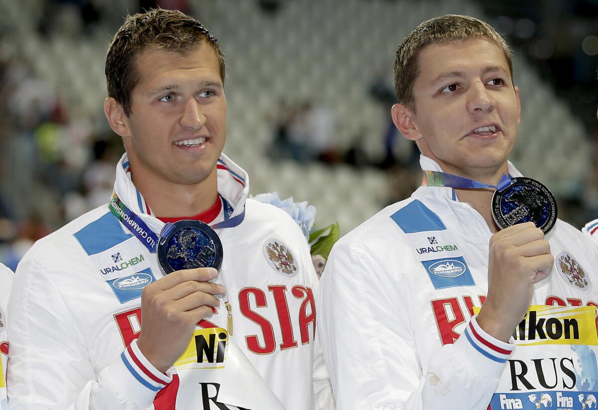 Nikita Lobintsev, left, and Vladimir Morozov hold up their silver medals at the swimming world championships on Aug. 2, 2015.
