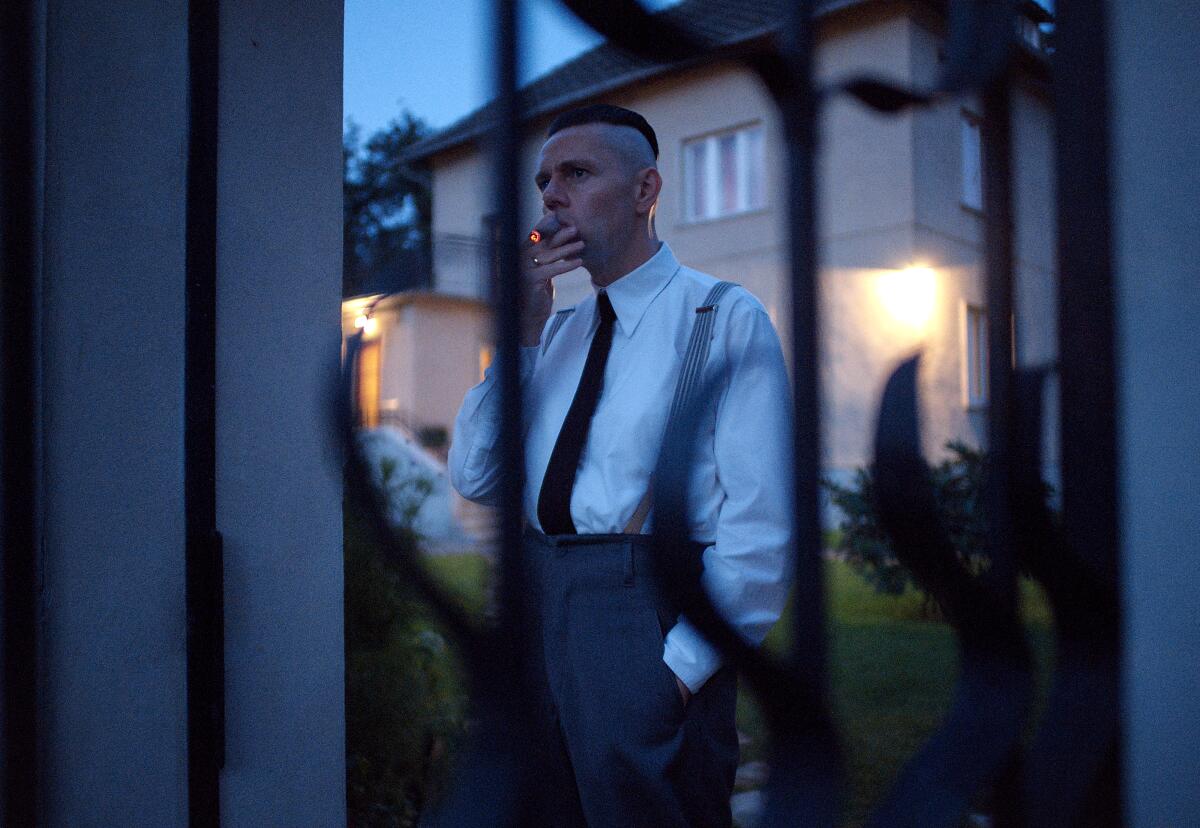 A man smokes outside his home at twilight.