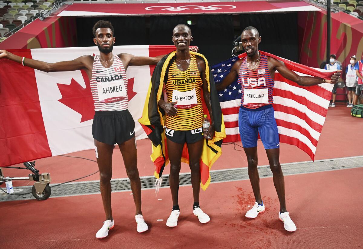 Gold medalist Joshua Cheptegei, center, is flanked by silver medalist Mohammed Ahmed, left, and bronze medalist Paul Chelimo.