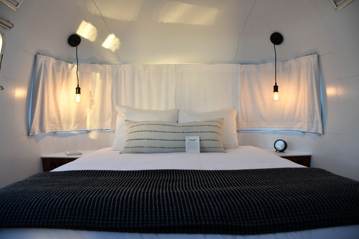 A bed flanked by Edison bulb sconces in an Airstream.
