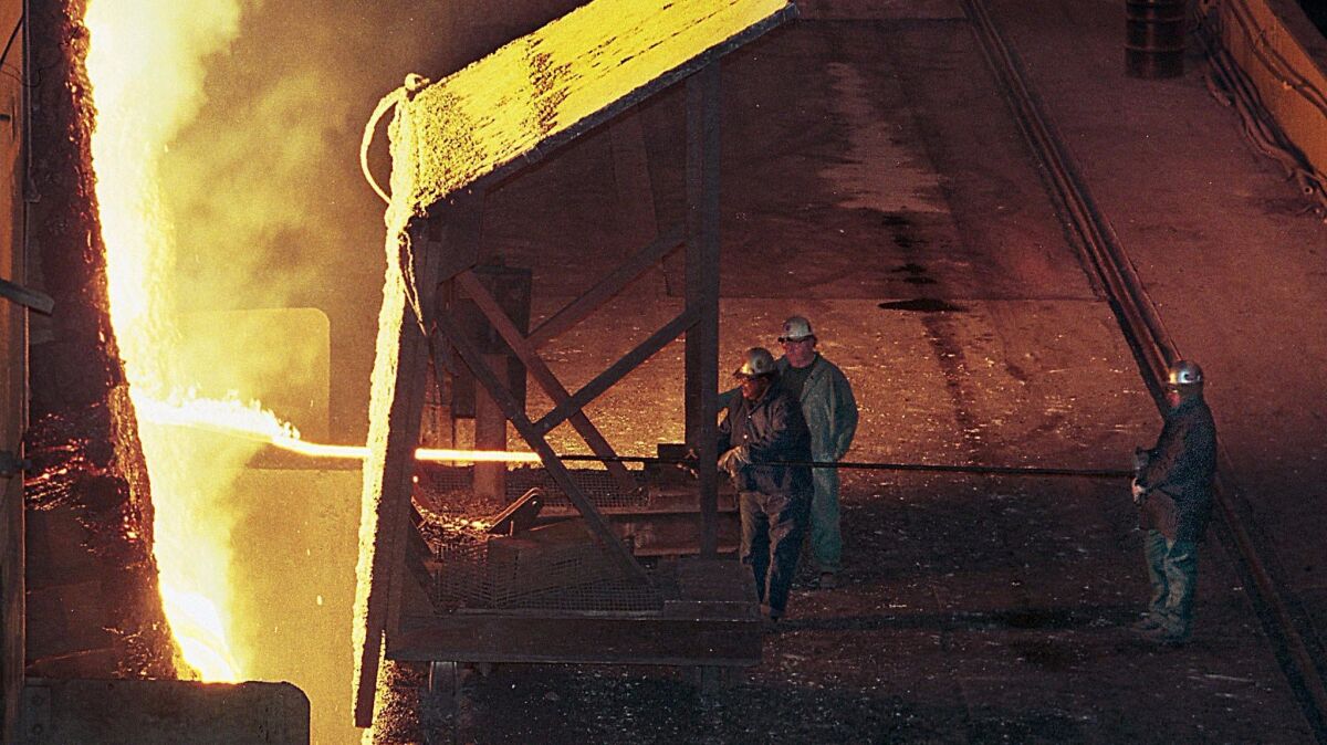 Steel workers take a sample from one of two basic oxygen furnaces at Bethlehem Steel's Sparrows Point facility near Baltimore, Maryland, on March 11, 2002.