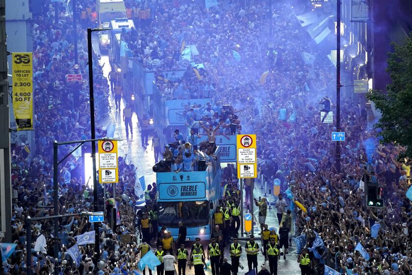 Jugadores del Manchester City recorren las calles de la ciudad en autobús descapotable para festejar con la afición tras ganar la tripleta de títulos el lunes 12 de junio del 2023. (Danny Lawson/PA via AP)