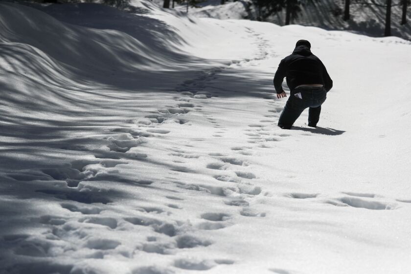 CRESTLINE, CA - MARCH 07: Sandals Church volunteer Dave Mack postholes through deep snow as he checks on area residents in the San Bernardino Mountain community on Tuesday, March 7, 2023 in Crestline, CA. (Brian van der Brug / Los Angeles Times)
