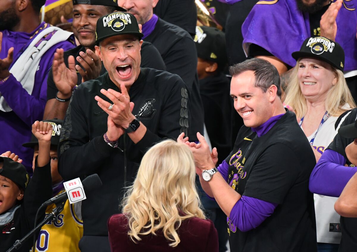Rob Pelinka, left, and coach Frank Vogel, facing Jeanie Buss, clap in celebration of the Lakers win.