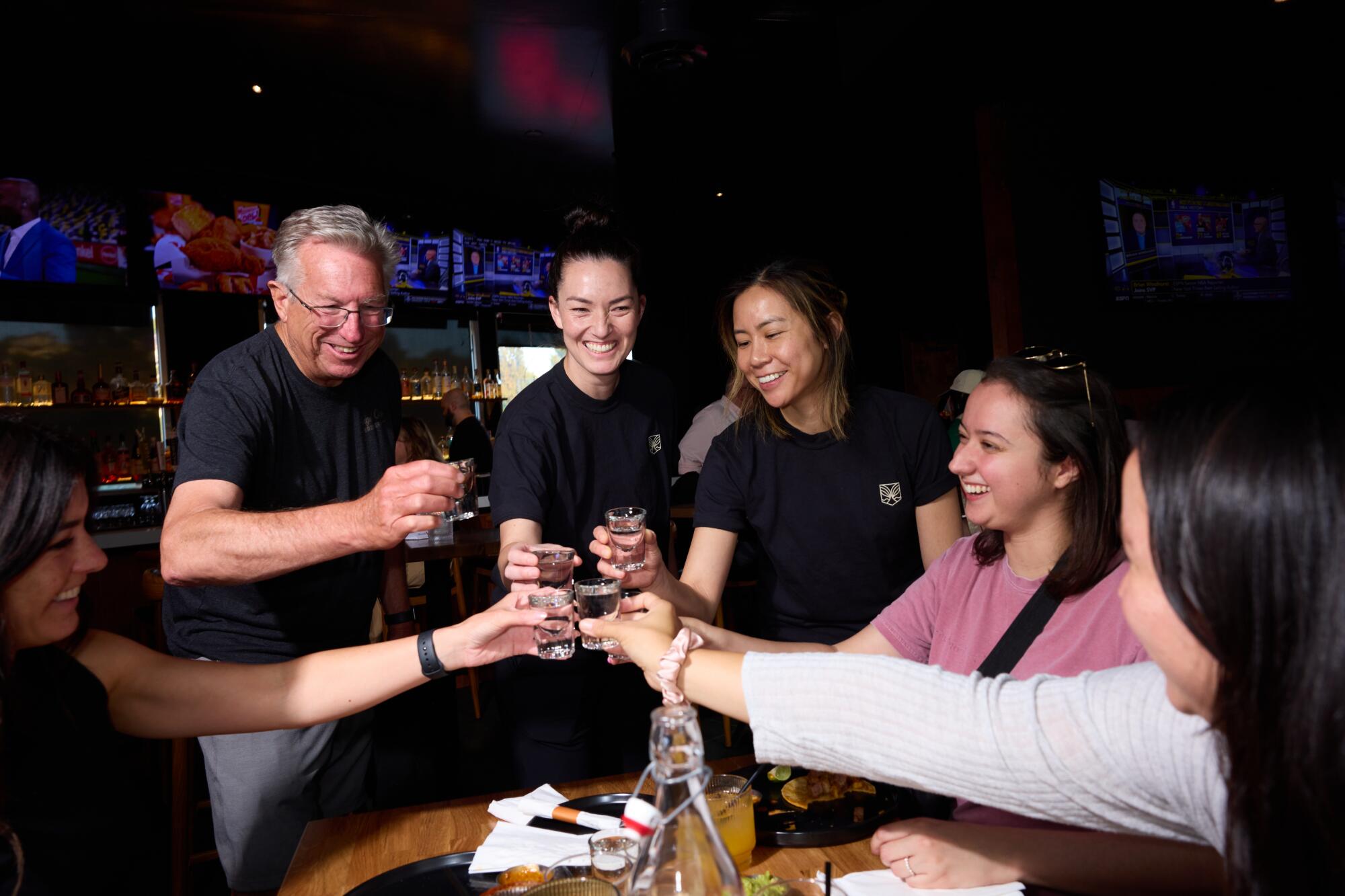 Six people clink glasses.