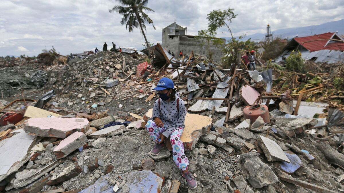 A woman sits on a pile of rubble in an area devastated by an earthquake in the Balaroa neighborhood of Palu, Indonesia, on Oct. 8.