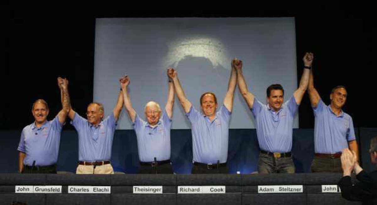 A proud lead team of John Grunsfield, Charles Elachi, Pete Theisinger, Richard Cook, Adam Steltzner and John Grotzinger, triumphantly raise their hands at JPL after the rover Curiosity successfully landed on the Red Planet.
