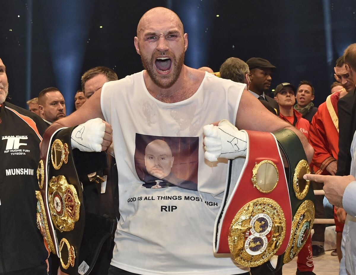 Britain's new world champion Tyson Fury celebrates with the WBA, IBF, WBO and IBO belts after winning the world heavyweight title fight against Ukraine's Wladimir Klitschko in the Esprit Arena in Duesseldorf, western Germany, Sunday, Nov. 29, 2015. (AP Photo/Martin Meissner)