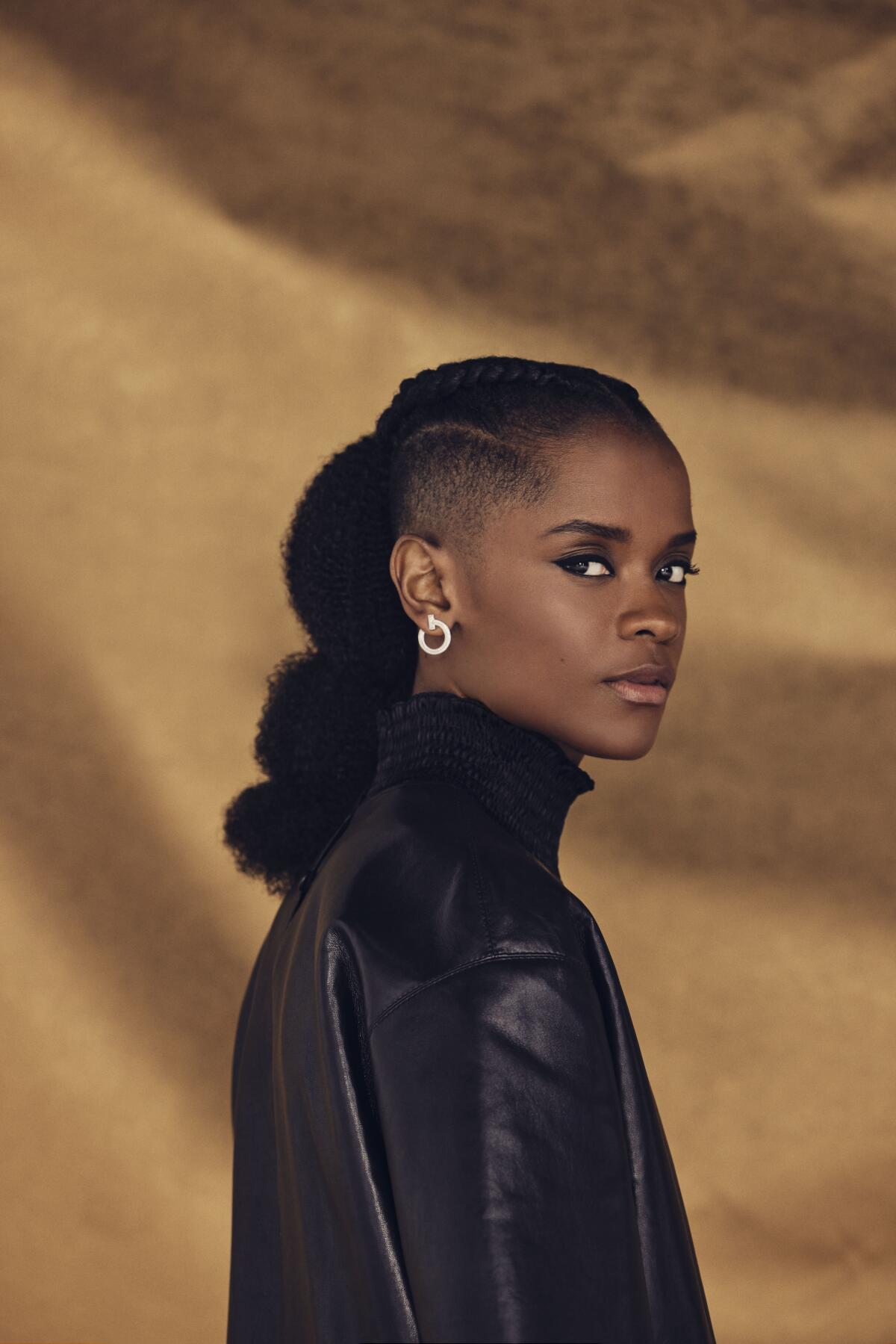 Letitia Wright wears a high-necked black top for a portrait.