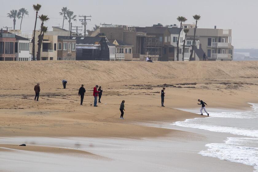 Orange County, CA - December 23: Beachcombers along the shore at Seal Beach are out for the large King Tide hitting the coast this week on Friday, Dec. 23, 2022 in Orange County, CA. (Brian van der Brug / Los Angeles Times)