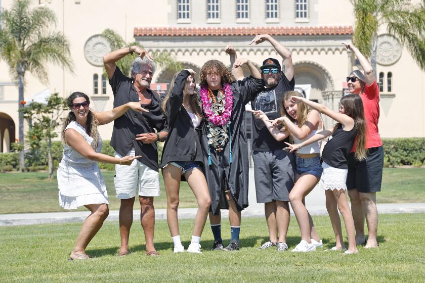 Graduate Brandon Ferrin, center, is the center of attention from his family including mom Jana, grandpa Larry Petersen, girlfriend Kamy Truelove, father Josh, cousins Makena and Isabel, and grandma Peggy, from left, just before the drive through graduation at Huntington Beach High School. Ferrin was a football and lacrosse standout before school shutdown in March.