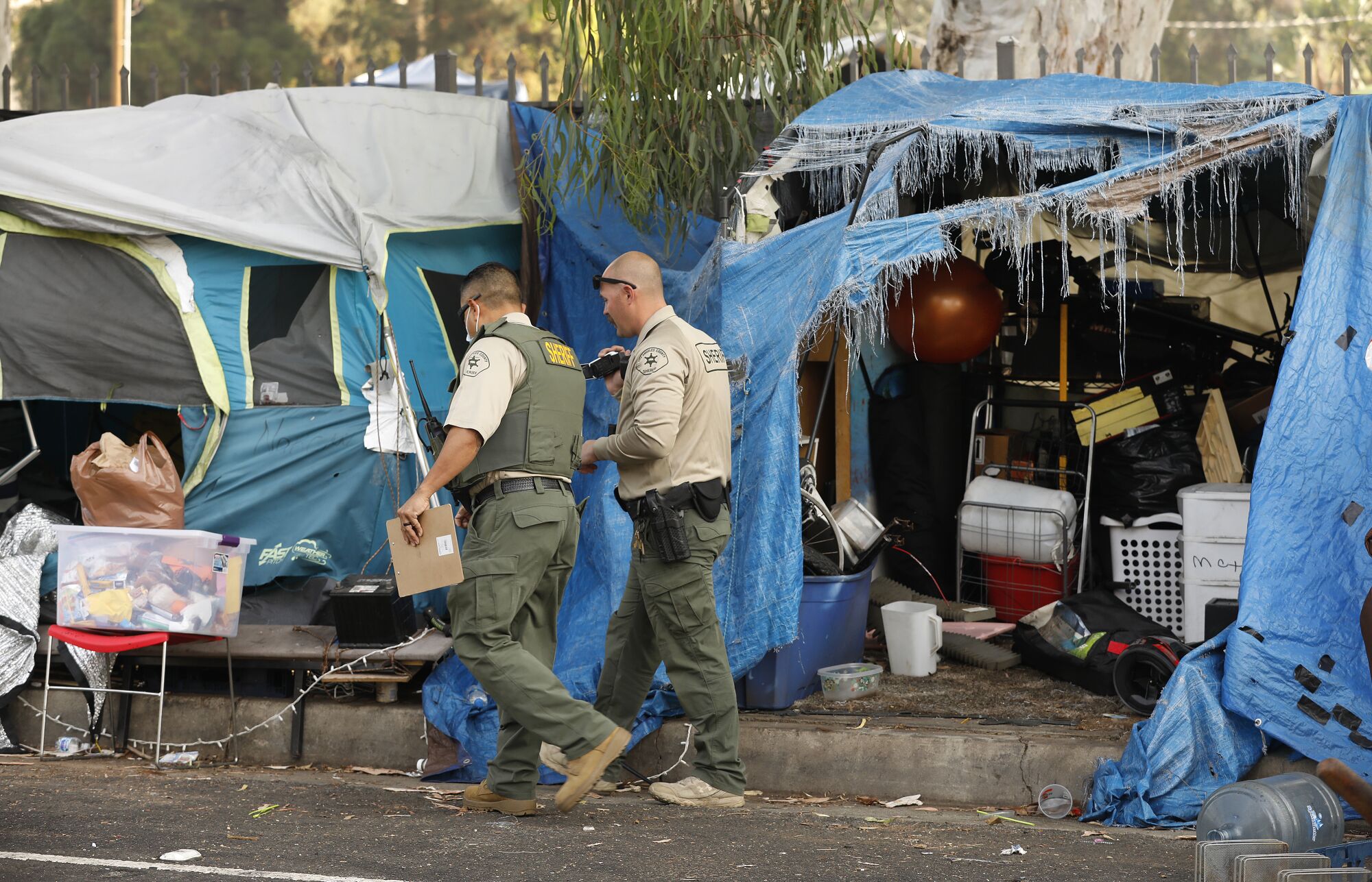 Los Angeles County Sheriff's officials walk through a homeless encampment
