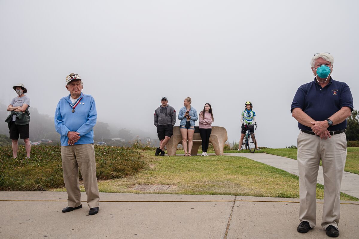 A few spectators watch at a distance during a Memorial Day service May 25 at Mount Soledad National Veterans Memorial in La Jolla. Due to restrictions caused by the coronavirus pandemic, the remembrance was shown online and not open to the public.