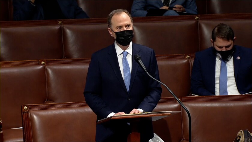 A man with a face mask stands behind a lectern.