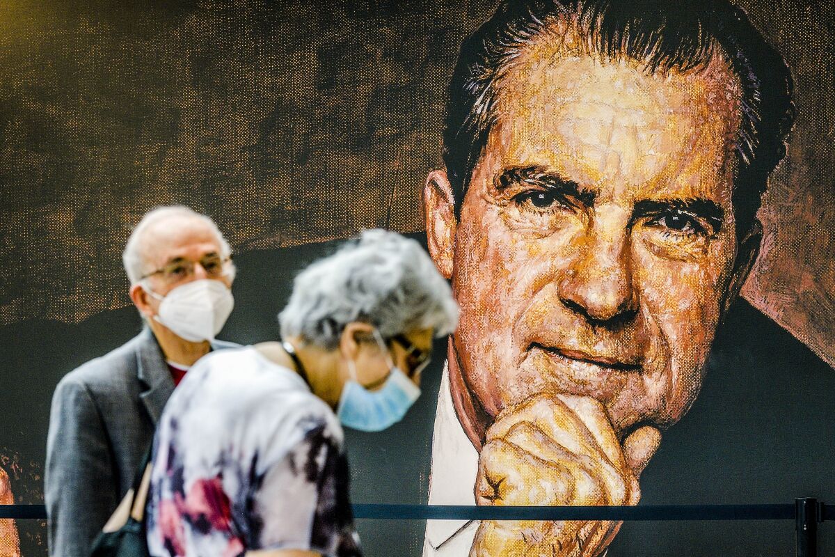 Visitors stand near a large mural of President Nixon.