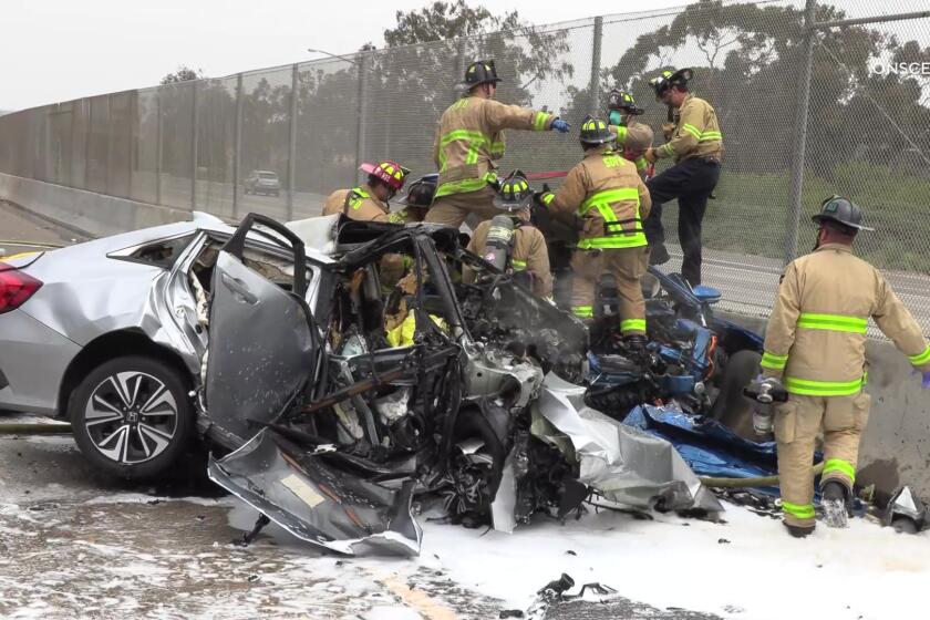 San Diego Fire-Rescue firefighters on and near two cars after a collision