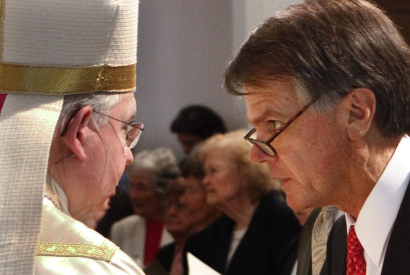 David W. Burcham, right, greets Archbishop Jose Gomez at the Mass for his inauguration as president of Loyola Marymount University in 2011. Burcham became the first lay person to hold that job in the school's 100-year history.