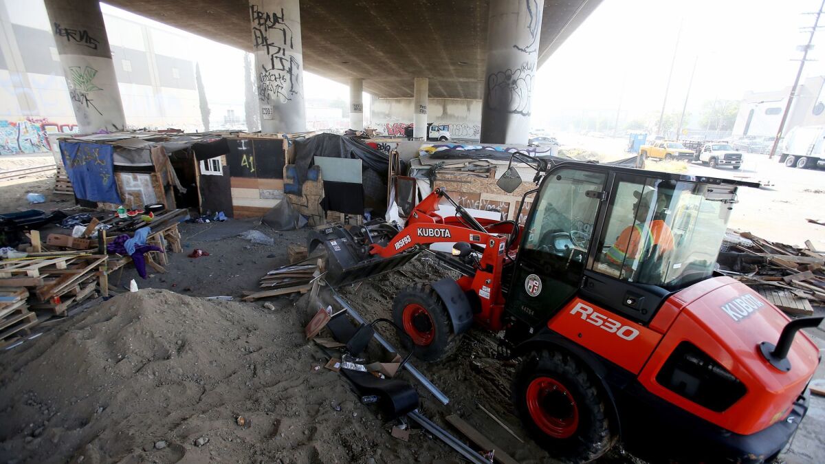 A worker clears a homeless encampment underneath the Santa Fe Avenue Bridge in Vernon in December.