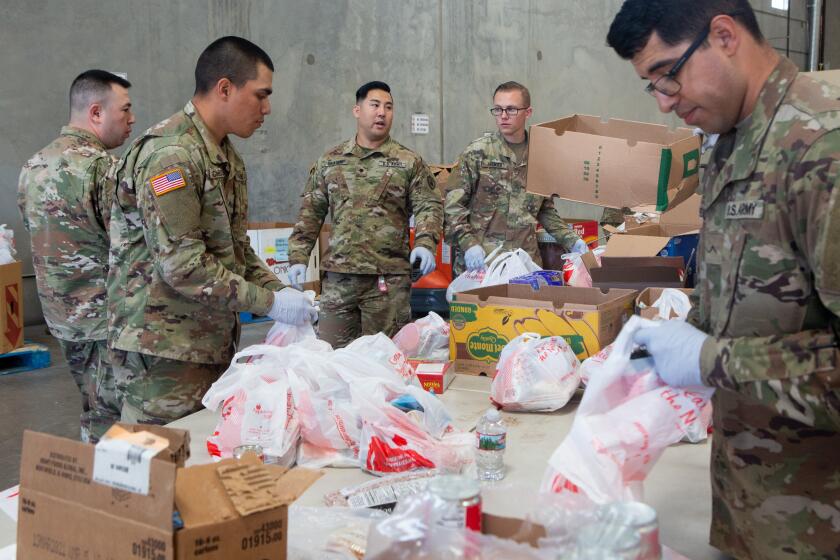 INDIO, -MARCH 26, 2020: Members of the 315 Vertical Construction Company (VCC) unit pack bags of food at the FIND Food Bank in Indio, Calif. Earlier this week, Govenor Gavin Newsom deployed the National Guard to communities to help staff local agencies suffering from a lack of workers and volunteers because of Gov. Newsom's stay at home order. (Gabriella Angotti-Jones/Los Angeles Times)