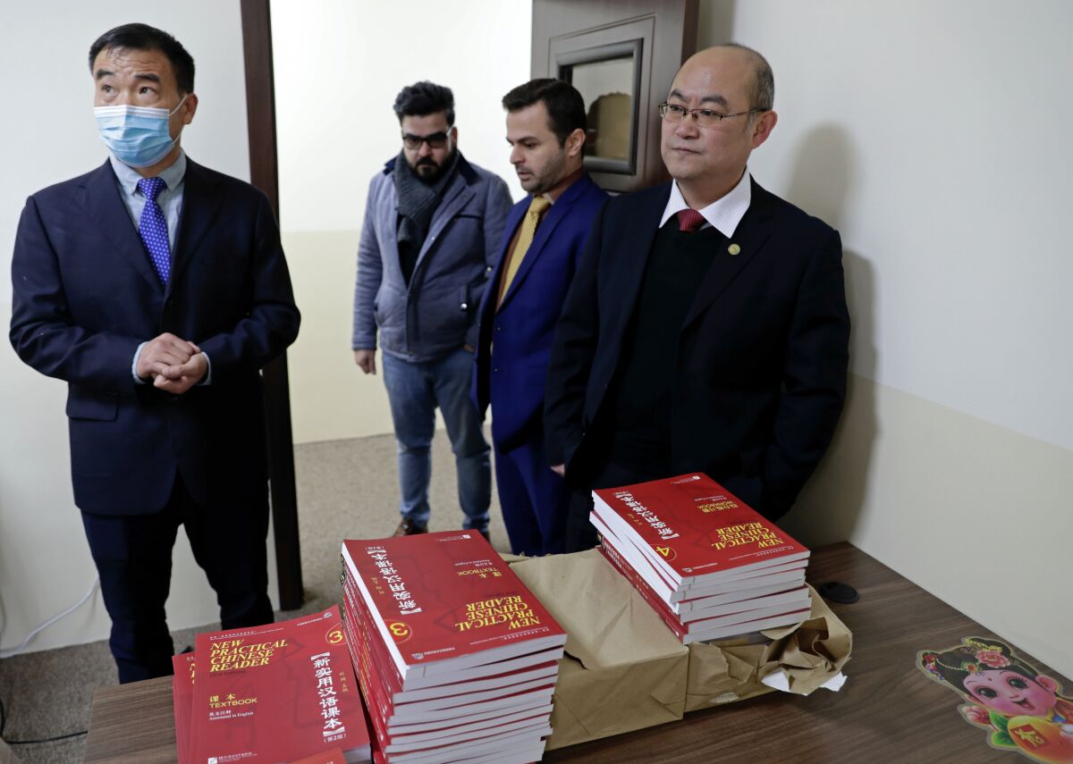 Chinese teachers and officials stand in front of Chinese language books.