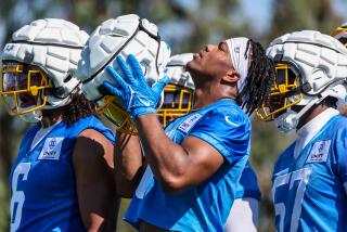 Chargers rookie linebacker Daiyan Henley puts on his helmet during training camp.