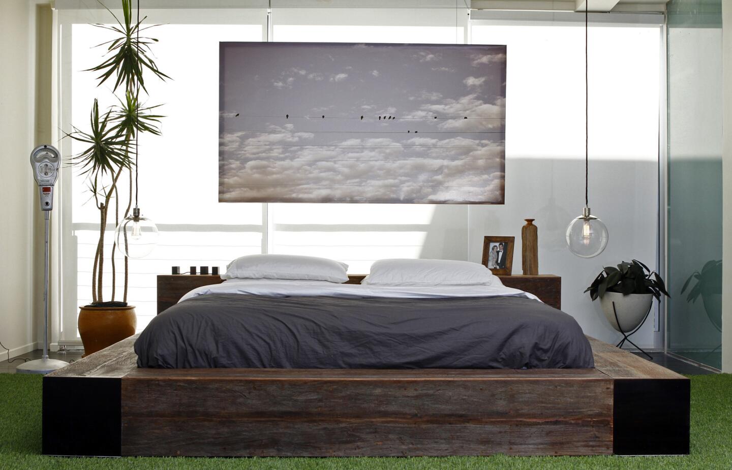 Instead of a traditional headboard, a floating photo on canvas by Alysia Cotter backs the bed. The lights are inexpensive pendants from West Elm. Full gallery