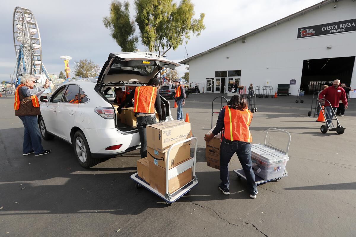 Volunteers unload donations for Share Our Selves' 50th annual Adopt A Family program Wednesday at the OC Fair & Event Center in Costa Mesa. The program helps struggling Orange County families by providing gifts and food for the holidays.