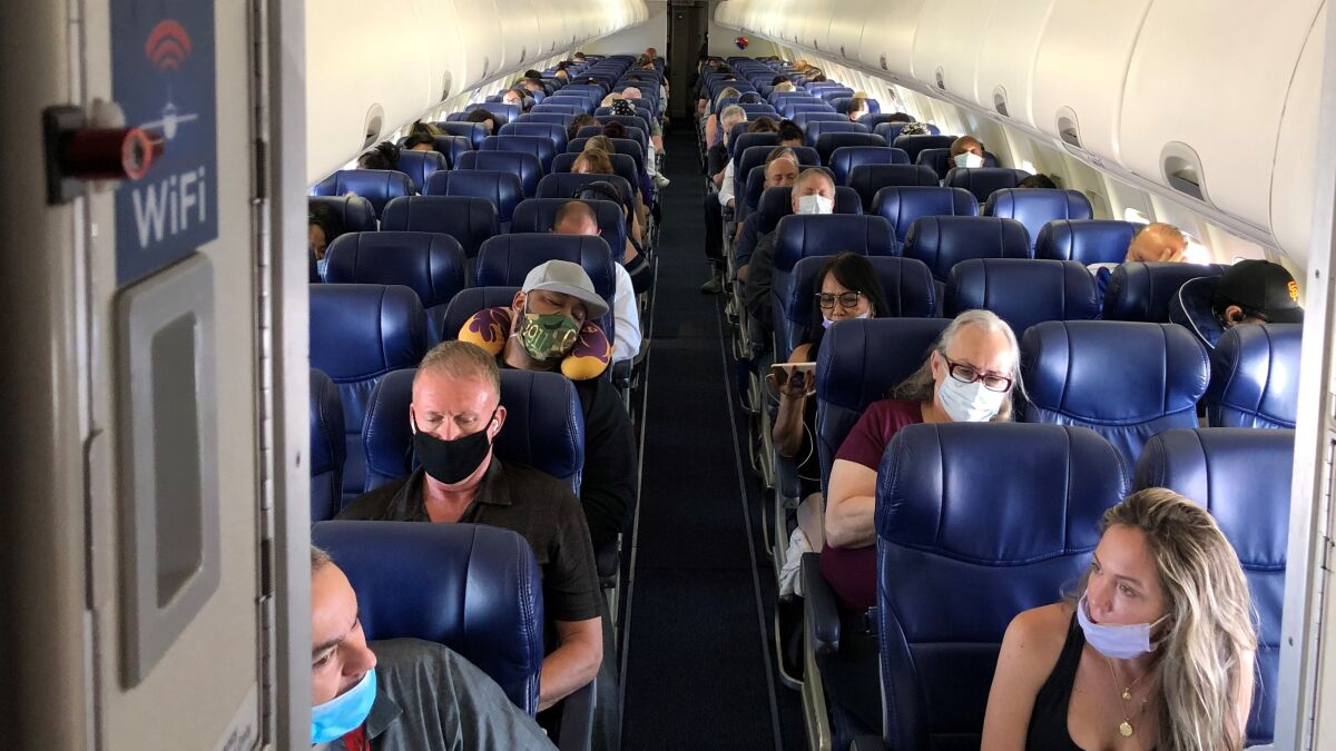 Masked passengers sit inside an airplane