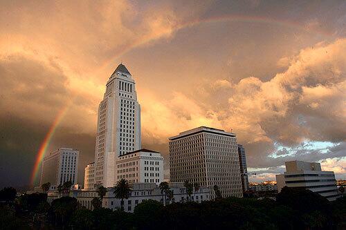 A rainbow forms over Los Angeles City Hall at sunset after a stormy day.