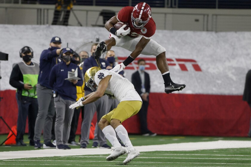Alabama running back Najee Harris (22) hurdles Notre Dame cornerback Nick McCloud (4) as he carries the ball for a long gain in the first half of the Rose Bowl NCAA college football game in Arlington, Texas, Friday, Jan. 1, 2021. (AP Photo/Michael Ainsworth)