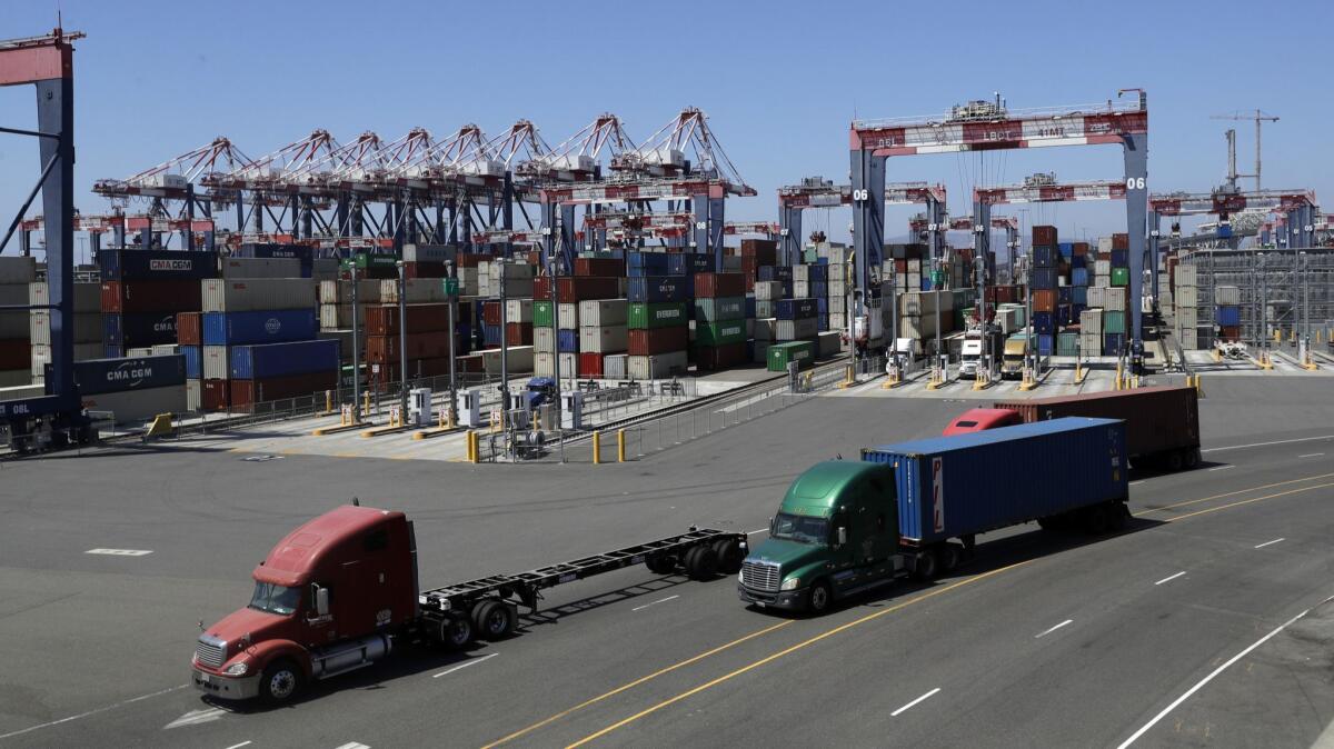 Trucks travel along a loading dock at the Port of Long Beach.