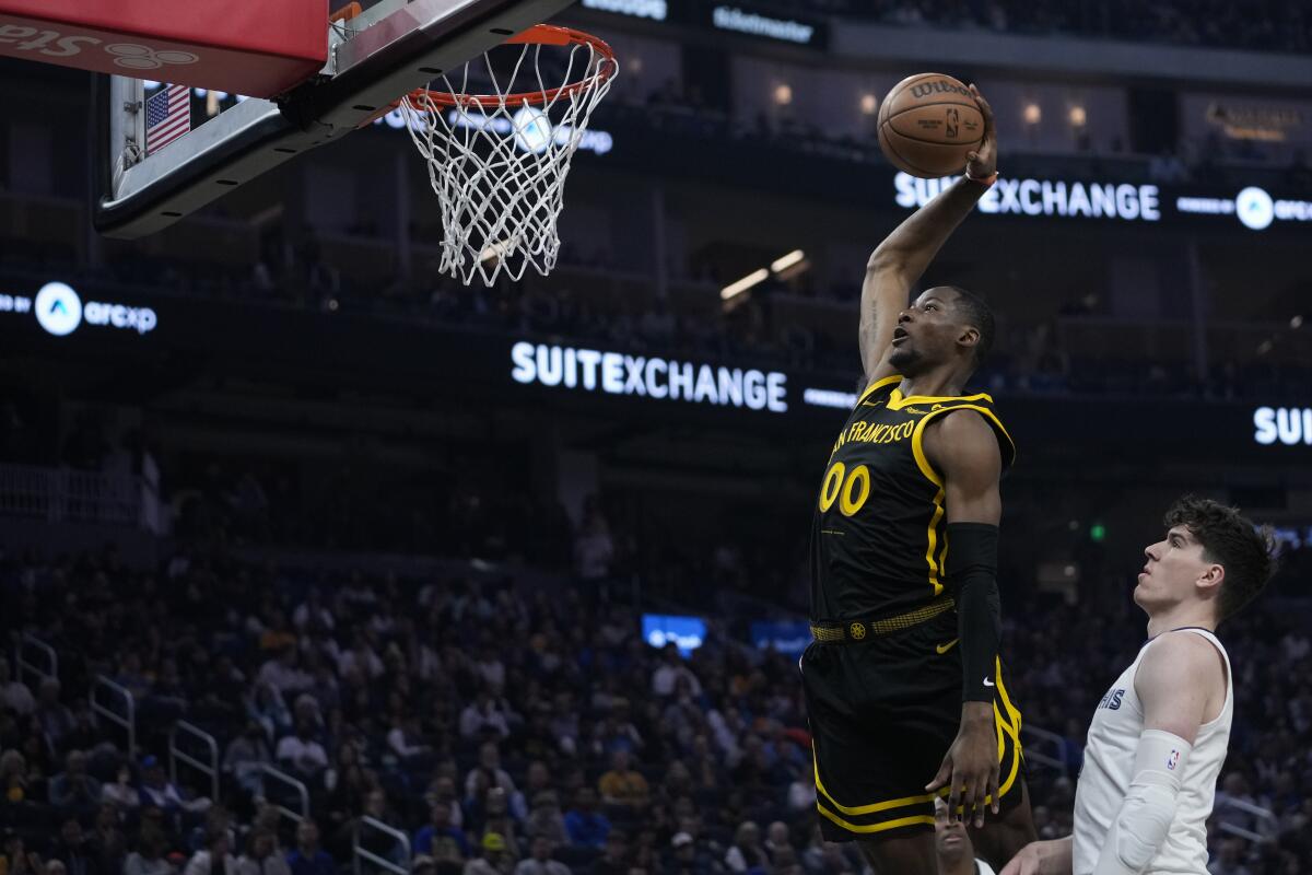 Golden State Warriors forward Jonathan Kuminga (00) dunks next to Memphis Grizzlies forward Jake LaRavia, right, during the first half of an NBA basketball game Wednesday, March 20, 2024, in San Francisco. (AP Photo/Godofredo A. Vásquez)