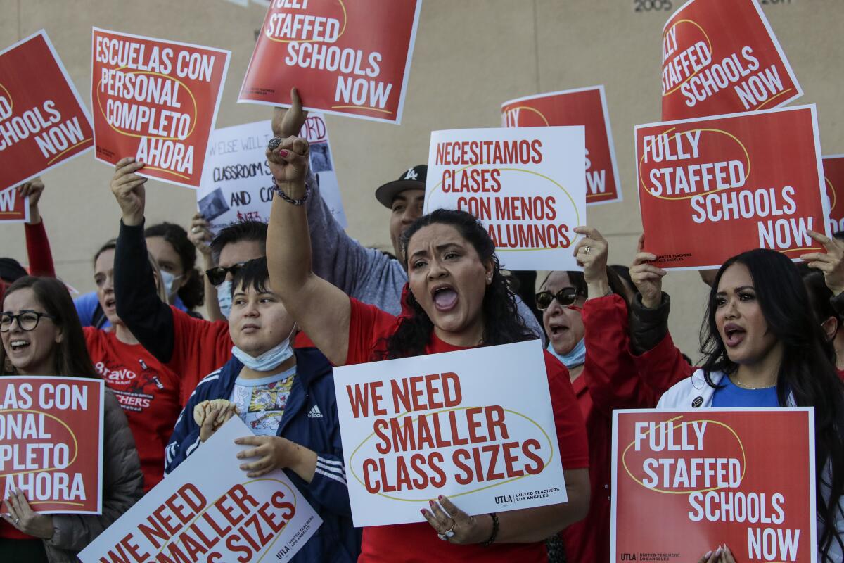 People hold protest signs calling for smaller classes and better school staffing.