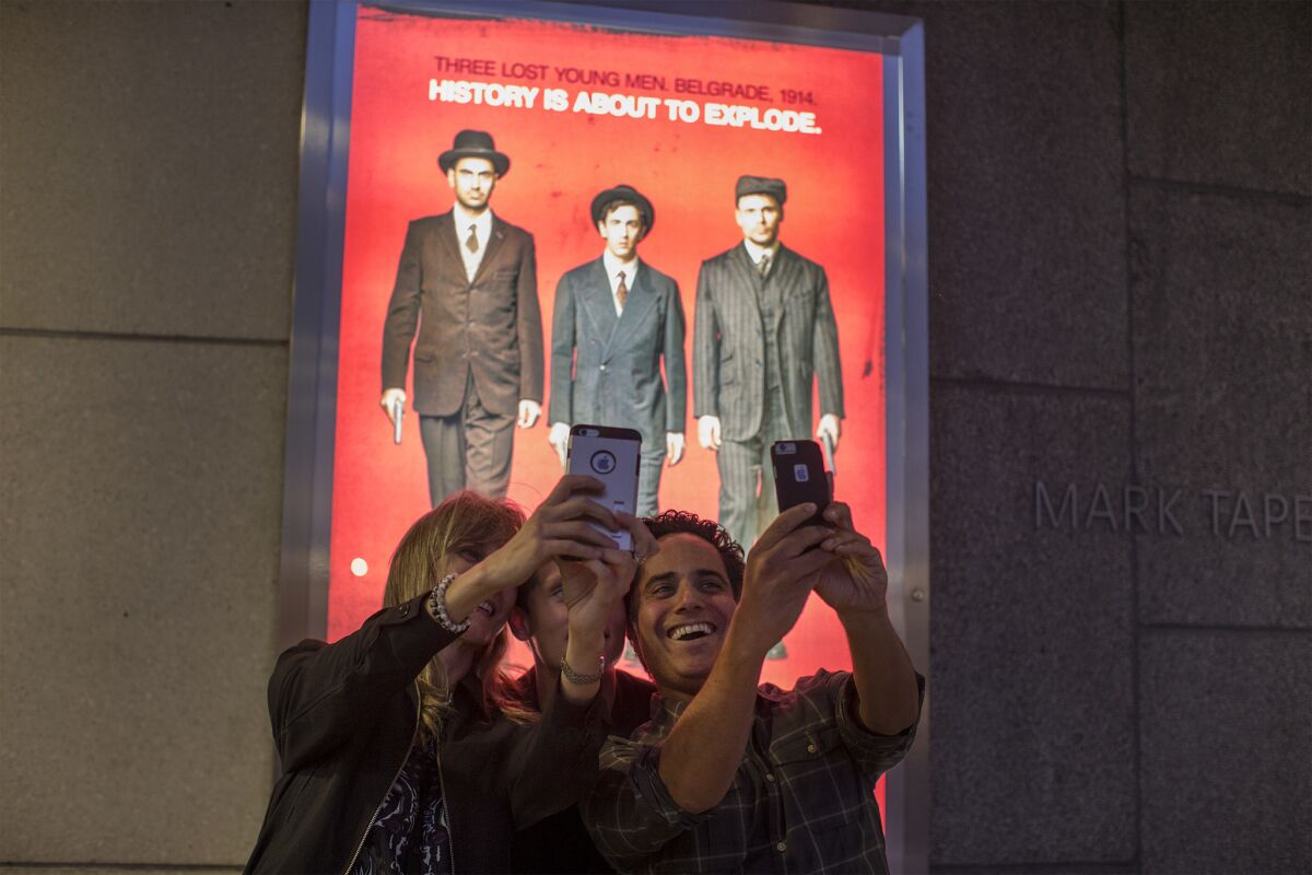 LOS ANGELES, CA - APRIL 25, 2017 : Playwright Rajiv Joseph,right, takes a selfie with friends in front of his play's poster on opening night of a preview performance for his new play "Archduke" on April 25, 2017 at the Mark Taper Theatre in Los Angeles, California.(Gina Ferazzi / Los Angeles Times)