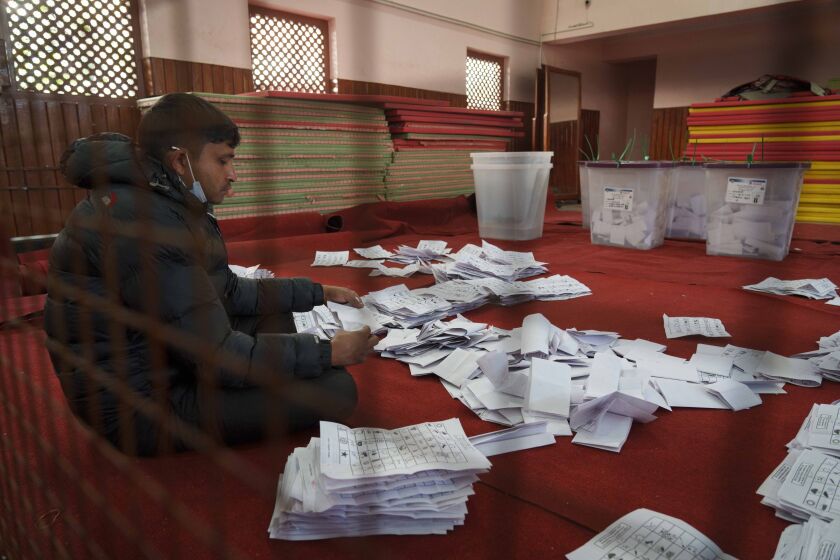 FILE- An election commission staff separates ballot papers to count a day after the general election in Kathmandu, Nepal, Nov. 21, 2022. Nepal has finished counting the votes that were cast in the Nov. 20 parliamentary elections, an election official said Wednesday, in polls that will ultimately determine the next prime minister. But formation of a new government could take days as no single party has secured a majority in the House of Representatives, the lower house of Parliament. (AP Photo/Niranjan Shrestha, File)