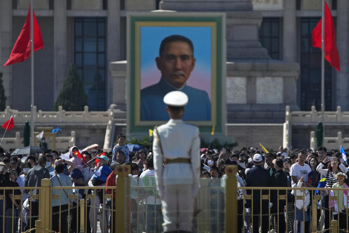 Visitors gather near a large portrait of a man in Tiananmen Square.